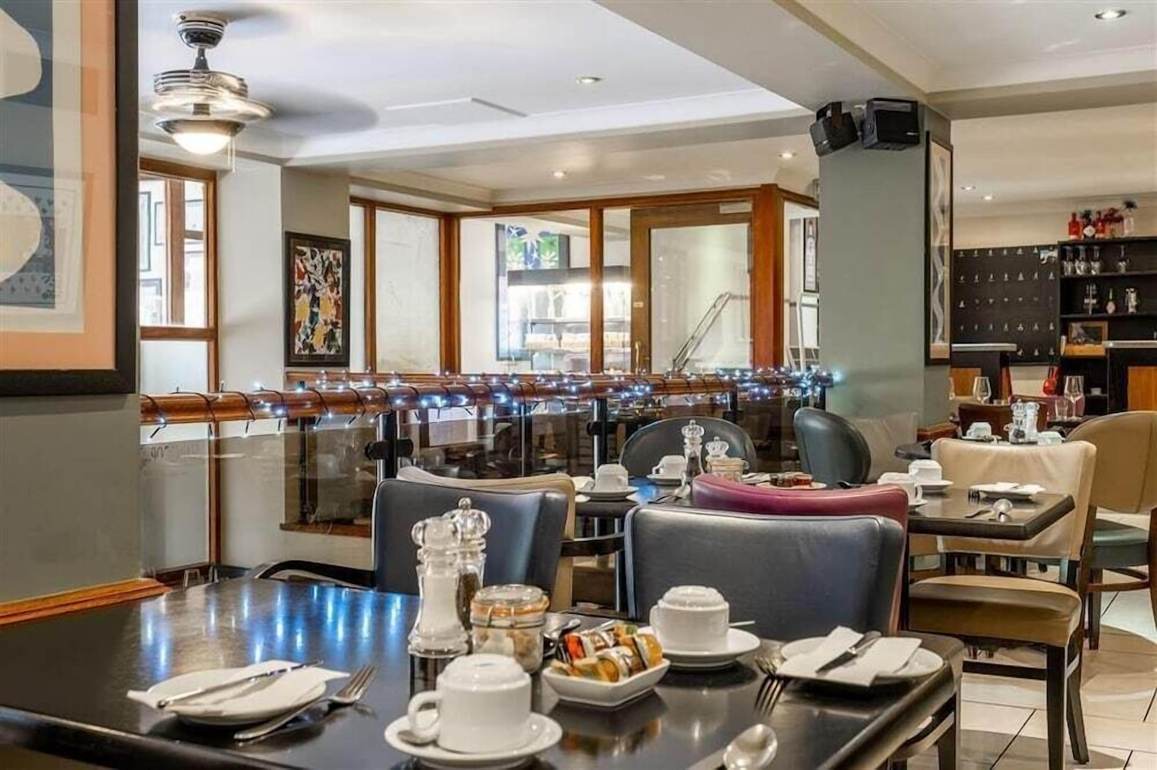 A dining area with tables set for breakfast, a bar area, and a view of the outside.