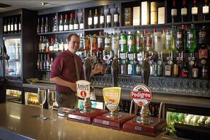Un bar où l’on peut voir de nombreuses bouteilles de spiritueux et trois robinets à bière portant les noms « Abbott Ale », « Cold » et « Pedigree ».
