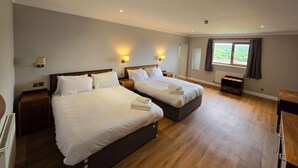 A hotel room with two beds, bedside lamps, a radiator, and a window with curtains. - Staindrop Lodge Hotel (Sheffield)