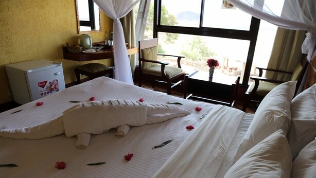 Una habitación de hotel con cama, escritorio, silla, una mesita y ventana con vistas.