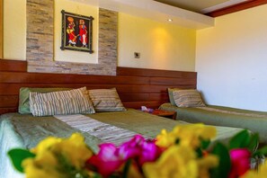 A hotel room with two beds, wooden headboards, a stone accent wall, and a framed artwork above the beds. - Voi Safari Lodge (Voi)