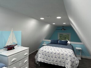 A bedroom with a bed, dresser, and a sailboat model.