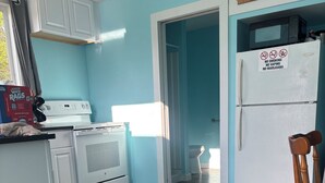 Une cuisine avec des meubles blancs, une cuisinière, un four à micro-ondes et un réfrigérateur.