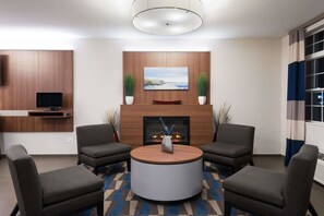 A modern lobby with a fireplace, seating area, and a flat-screen TV mounted on the wall. - Microtel Inn & Suites By Wyndham Windham (Windham)