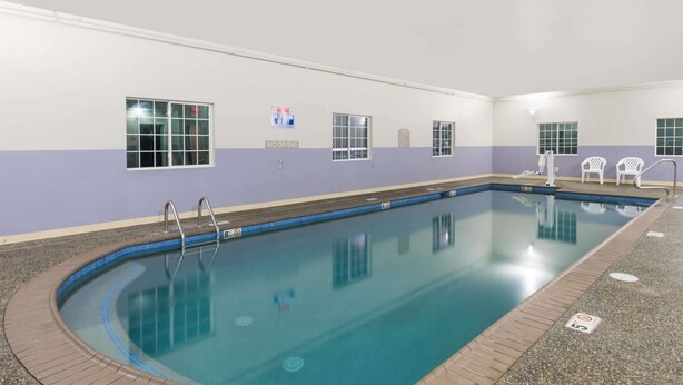 An indoor swimming pool with a tiled floor, a no diving sign, and a no lifeguard on duty sign. - Microtel Inn & Suites By Wyndham Windham (Windham)