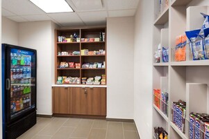 A vending machine with various beverages, a stocked shelf with snacks and drinks, and a storage cabinet.