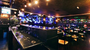 A bar area with a counter, seating, and a DJ booth.