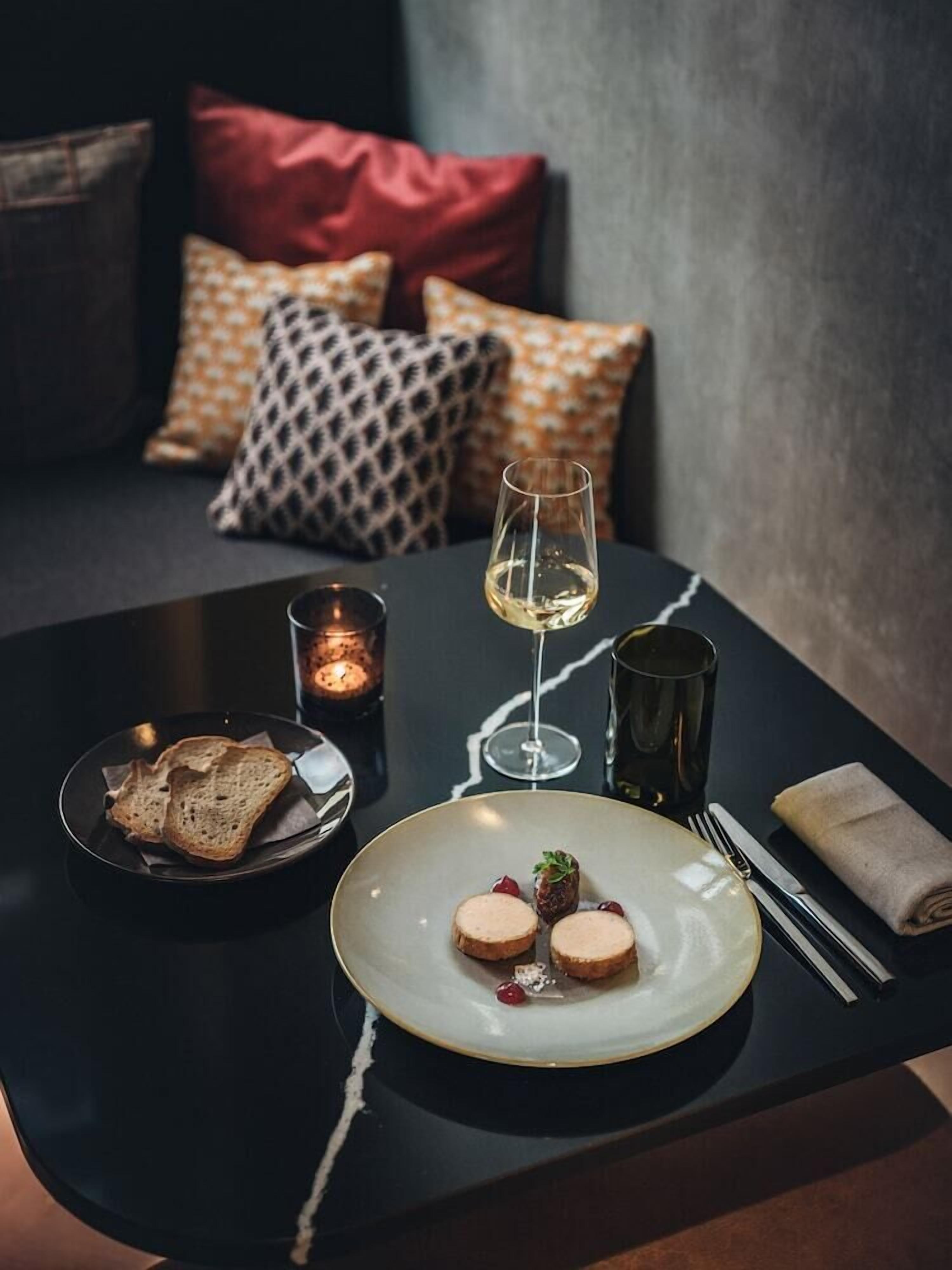 Una mesa de comedor con un plato de comida, una copa de vino y una vela.