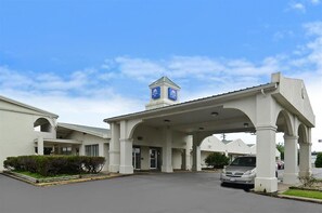 A hotel entrance with a covered walkway, a sign indicating it's a Marriott hotel, and a parking lot with a car. - Americas Best Value Inn Beaumont Tx (Beaumont)