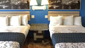 Une chambre d’hôtel avec deux lits, une table de chevet, deux lampes fixées au mur et deux tableaux représentant des paysages urbains.