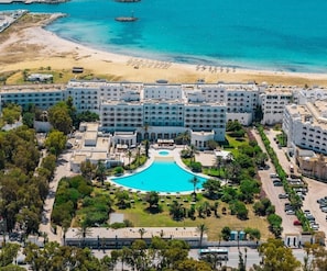 Un hotel con piscina centrale, fronte spiaggia e diversi edifici.