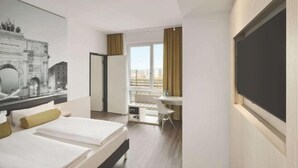 A hotel room with two beds, a desk, a chair, a large window with curtains, and a wall-mounted TV. - Premier Inn Hamburg City Berliner Tor (Hamburg)