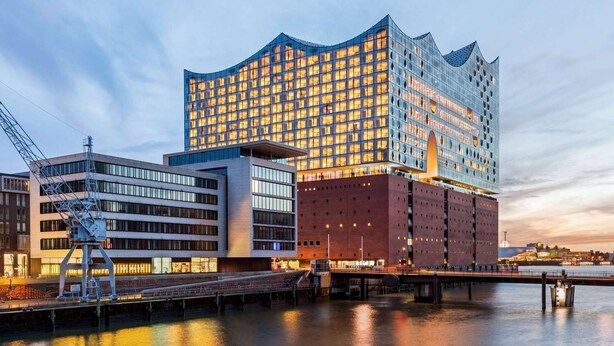 A modern hotel with a distinctive wavy facade, a waterfront location, and a bridge connecting to the building. - Premier Inn Hamburg City Berliner Tor (Hamburg)