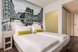 Una habitación de hotel con una cama, una mesita de noche y un mural en la pared con una vista urbana.