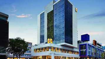 Ein modernes Hotel mit einer markanten vertikalen Begrünung, großen Fenstern und einer blau-weißen Fassade.