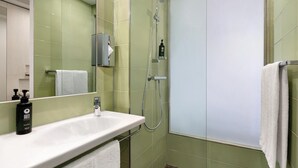 Un bagno con lavandino bianco, uno specchio, un portascopevoli e una doccia con porta in vetro.