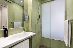 A bathroom with a white sink, a mirror, a towel rack, and a shower with a glass door. - Premier Inn Koblenz City (Koblenz)