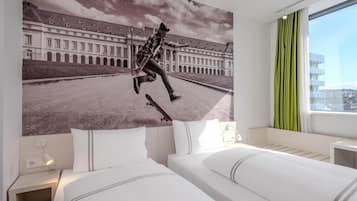 Ein Hotelzimmer mit einem Bett, einem Nachttisch, einer Wandlampe und einem großen Fenster mit Vorhängen.