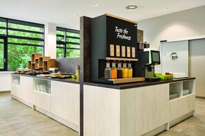 A modern kitchen area with a coffee station, a refrigerator, and a view of greenery outside. - Premier Inn Koblenz City (Koblenz)