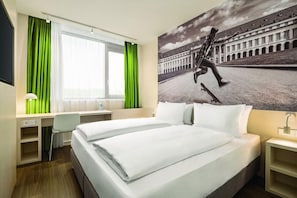 A hotel room with a bed, desk, and a large window with curtains. - Koblenz (Koblenz)