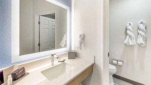 Une salle de bain avec un grand miroir, un lavabo, des toilettes et des serviettes accrochées au mur.