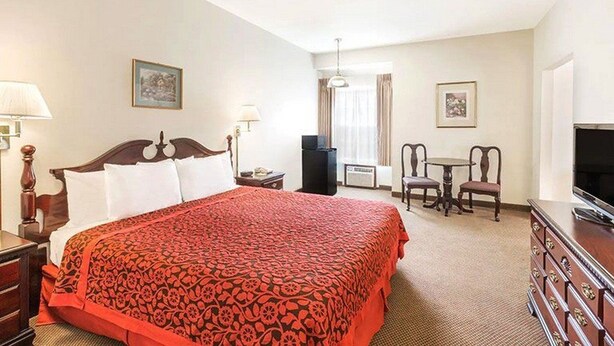 Une chambre d’hôtel avec un grand lit, un bureau, une chaise, une télévision et une commode.