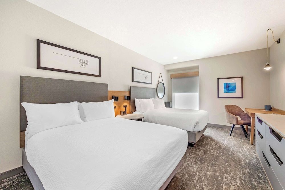 A hotel room with two beds, a desk, and a chair.