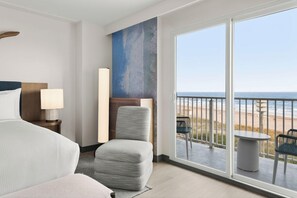 A hotel room with a bed, a chair, a table, and a balcony with a view of the beach. - Hotel Atlantic City Oceanfront Boardwalk (Atlantic City)