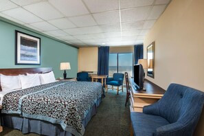 A hotel room with a bed, a desk, a chair, a TV, a lamp, a small table, and a window with curtains. - Days Inn Atlantic City Oceanfront Boardwalk (Atlantic City)