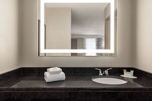 Un baño con un espejo grande, un lavabo y una toalla.