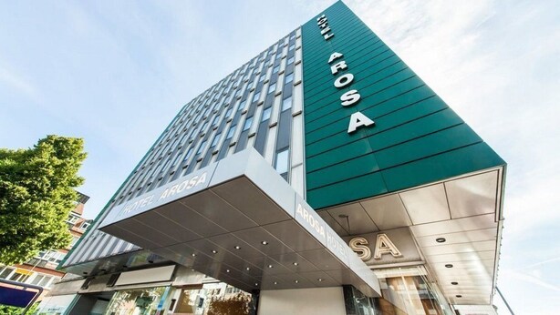 A modern hotel building with the name 'AROSA HOTEL' prominently displayed on the facade.