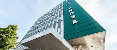 A modern hotel building with the name 'AROSA HOTEL' prominently displayed on the facade.