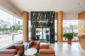 Eine Lobby mit Marmorwand, Ledersitzgelegenheiten und Blick auf die Straße.