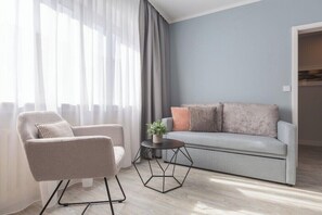 Ein modernes Wohnzimmer mit einem grauen Sofa, einem beigefarbenen Sessel und einem sechseckigen Couchtisch.