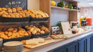 A breakfast buffet with various breads and pastries, a coffee sign, and kitchen appliances.
