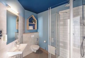 A bathroom with a shower, a sink, and a toilet. - Yggotel Solsort (Essen)
