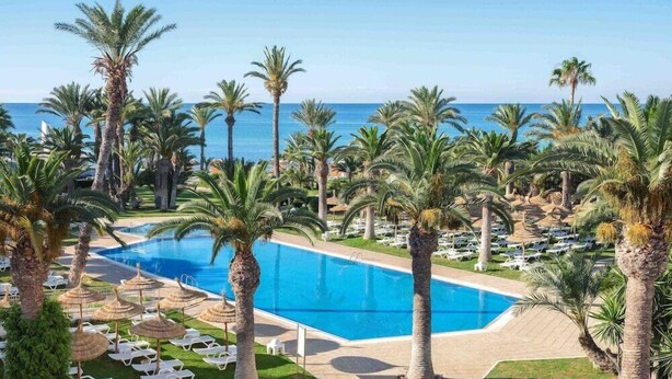 A resort with a large pool, palm trees, and a view of the ocean. - TUI Blue Palm Beach Hammamet (Hammamet)