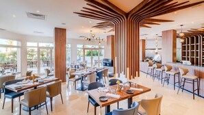 A modern restaurant with high ceilings, wooden accents, and a chef preparing food. - TUI Blue Palm Beach Hammamet (Hammamet)