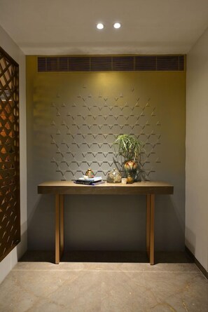 A room with a wall-mounted geometric pattern, a wooden table with decorative items, and a vent above the table. - THE Fern AN Ecotel Hotel Vadodara (Vadodara)