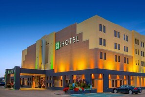 A multi-story hotel with a prominent 'HOTEL' sign, a parking lot, and a well-lit entrance.