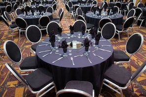 A banquet hall with round tables, black tablecloths, and chairs with black cushions. - Radisson Red Deer Hotel (Red Deer)