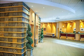 Un hall d’hôtel comprenant un comptoir d’accueil, un espace salon et un grand mur en pierre.