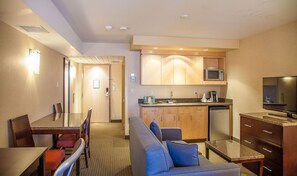 A hotel room with a kitchenette, a dining area, and a living room with a sofa and TV. - Radisson Red Deer Hotel (Red Deer)