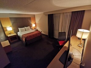 A hotel room with a bed, bedside tables, a desk, a chair, and a lamp. - Radisson Red Deer Hotel (Red Deer)