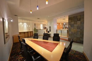 A conference room with a long table, black chairs, a reception desk, and a stone wall. - Radisson Red Deer Hotel (Red Deer)