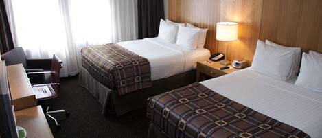 Ein Hotelzimmer mit zwei Betten, einem Schreibtisch, einem Stuhl, einer Lampe und einem Telefon.