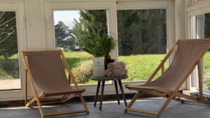 Ein Poolbereich mit zwei Liegestühlen und einem kleinen Tisch mit einer Pflanze.