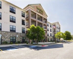 A multi-story hotel with a sign reading 'MarinStay Suites,' featuring a stone facade, multiple balconies, and a parking lot with handicapped parking spaces. - Mainstay Suites (Rogers)