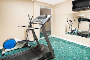 A fitness room with a treadmill, elliptical, and stationary bike, a television, and a mirror. - Super 8 by Wyndham Lamar (Lamar)