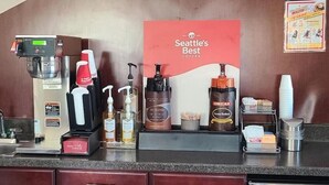A coffee station with a coffee machine, decaf coffee, and a Seattle's Best Coffee sign.